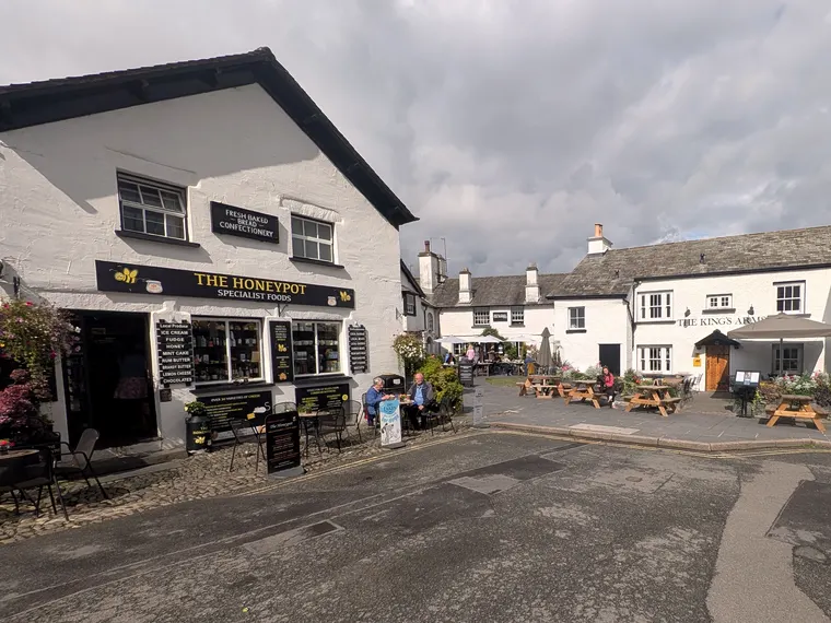 The square in Hawkshead in sunshine, with The Honeypot deli and the Kings Arms