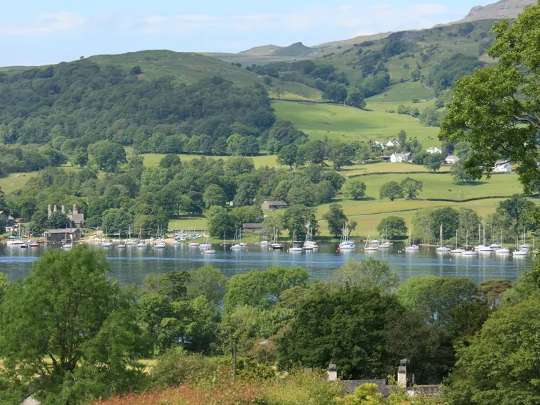 Boats moored on a Lake District lake below green fells